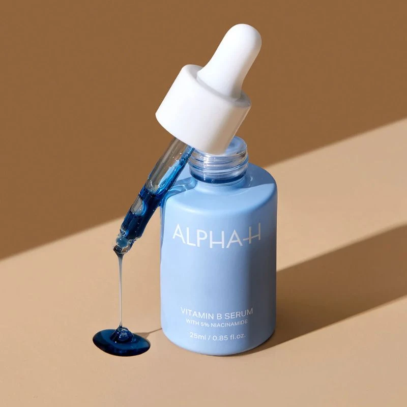 Blue Alpha-H Vitamin B Serum bottle with a dropper on a beige background.