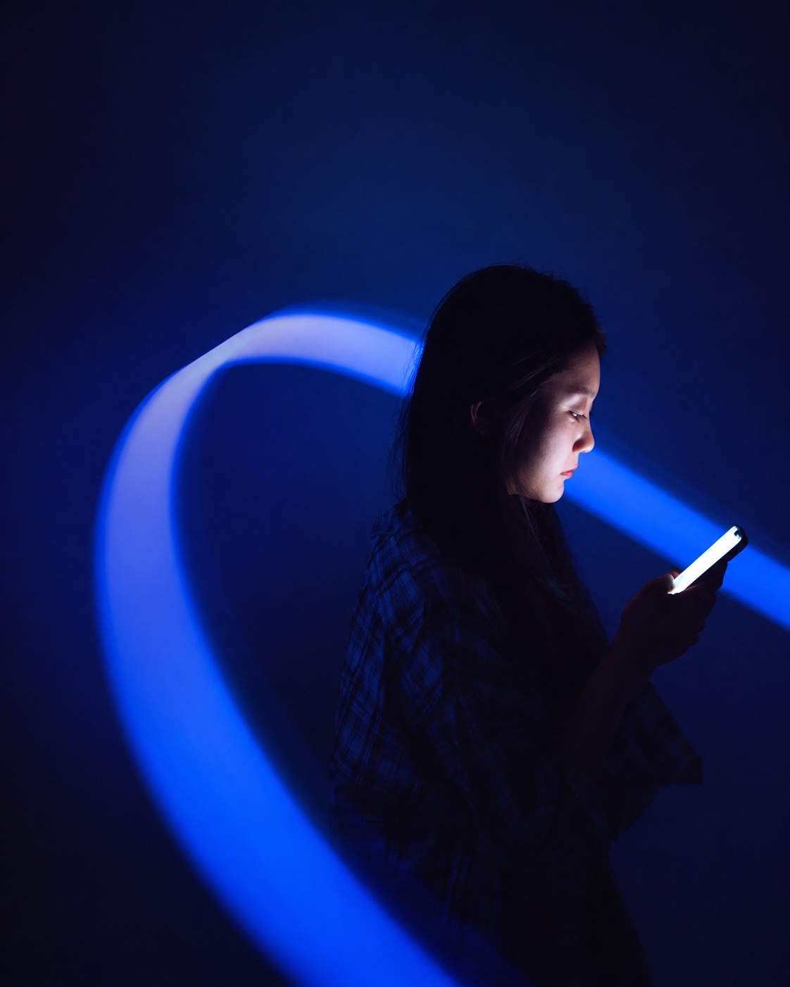 Woman using a smartphone surrounded by blue light