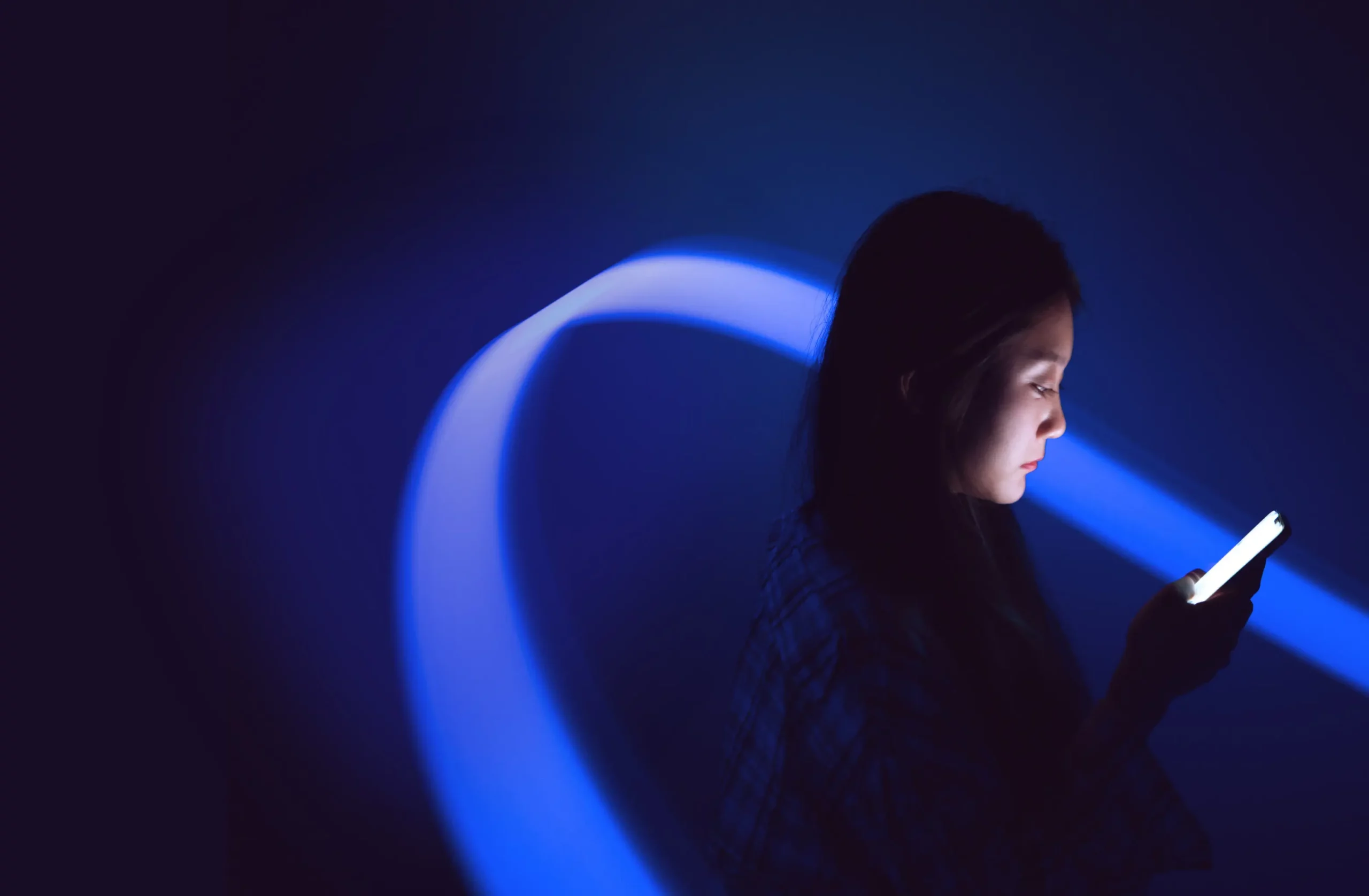 Vrouw met een smartphone in blauw licht, als beeld voor AI en hosting